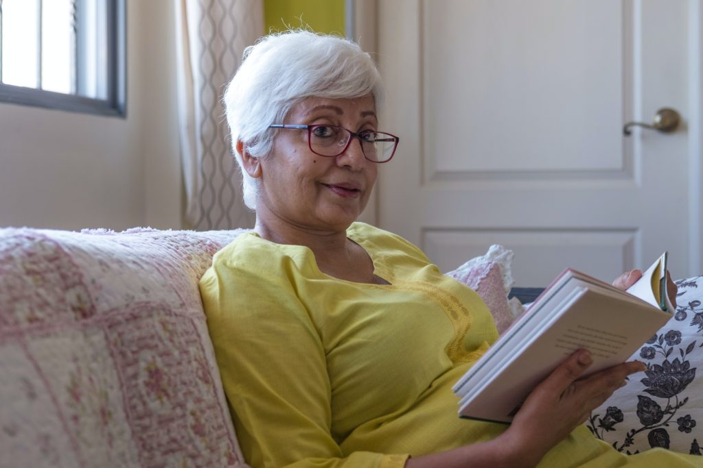 older woman reading book wearing red glasses